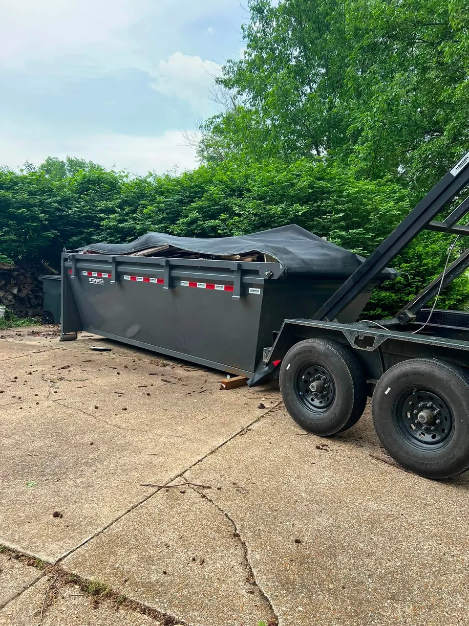 Loaded and tarped roll-off dumpster being hooked up for pickup