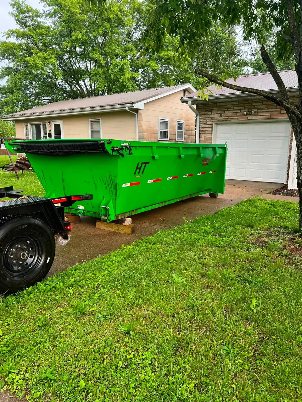Green TX2 roll-off dumpster beside a garage on a residential driveway in Franklin County, MO